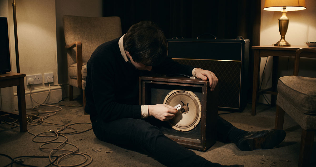 Teenage Dave Davies cuts an amplifier speaker cone with a razor blade in North London in 1964